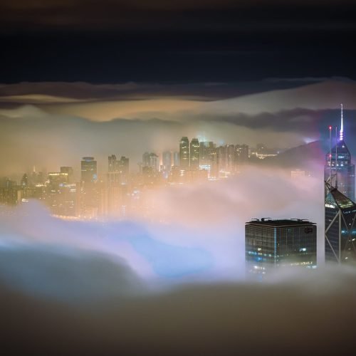 A mesmerizing shot of the skyscrapers of a city covered in mist at night